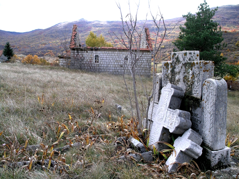 Zidina spaljene crkve i polomljeni spomenici na srpskom groblju u Donjim Rujanima